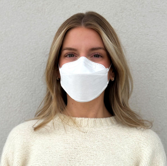 Front view of woman wearing small white KN95 earloop respirator style trifold face mask breatheTeq USA made in Canada