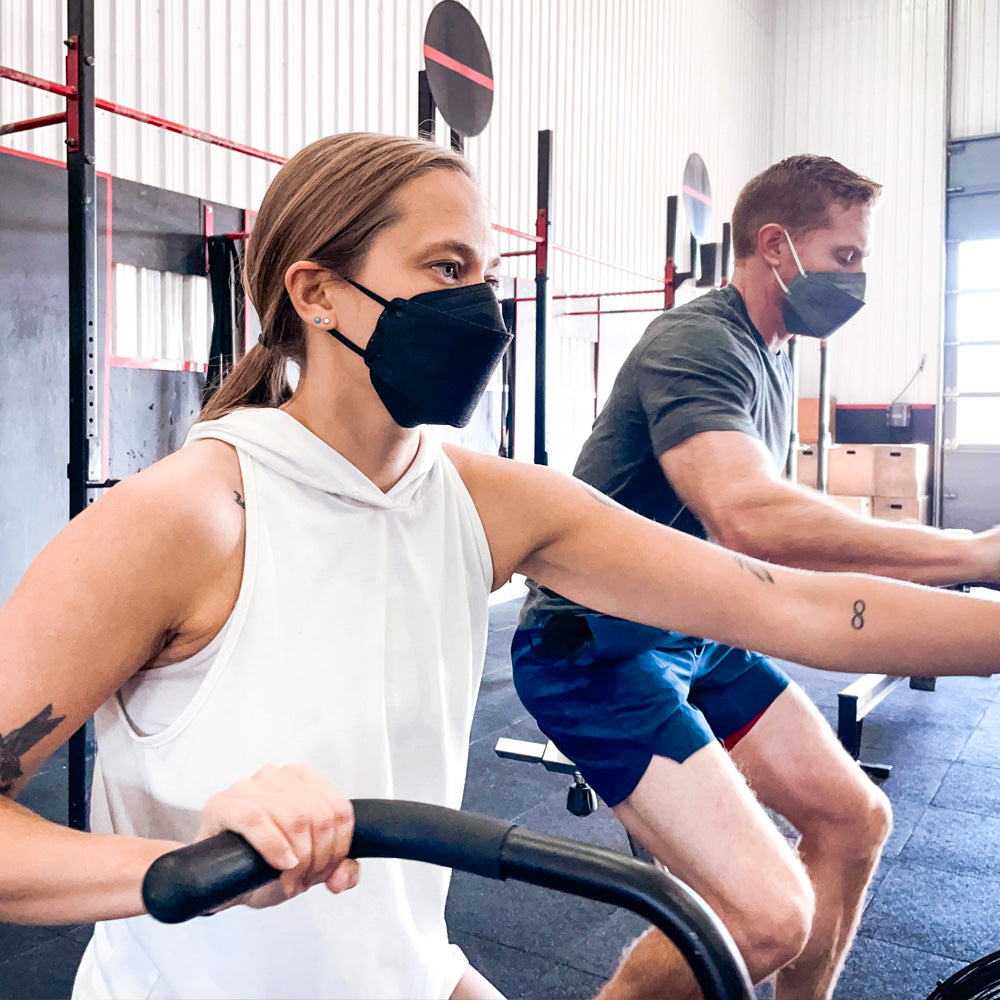 Man and woman wearing highly breathable KN95 face mask at the gym working out black and gray
